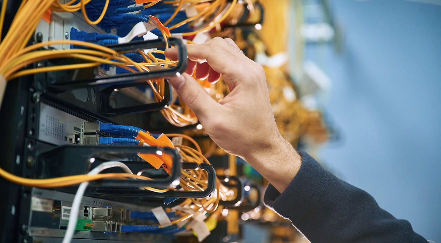 A person holds a cable in front of a server, preparing for a connection or maintenance task.